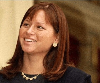 Sophie Belle Clapton's mother, Melia McEnery wearing purple outfit with a golden necklace.